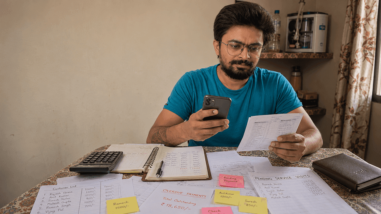 RO technician looking stressed at mobile phone representing monthly income uncertainty and financial planning problem